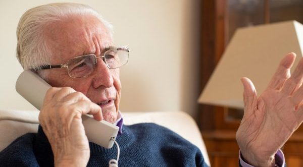 An elderly gentlemen speaks on the telephone
