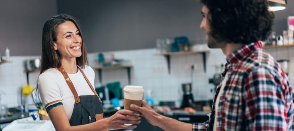 Small business owner handing coffee to customer