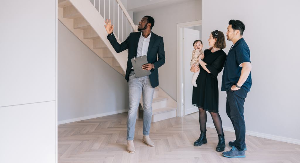 Real estate agent giving a house tour to a couple with a baby.