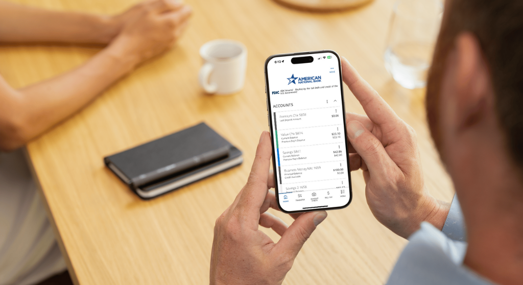Person holding a smartphone displaying ANB Go Business app, showing account balances.